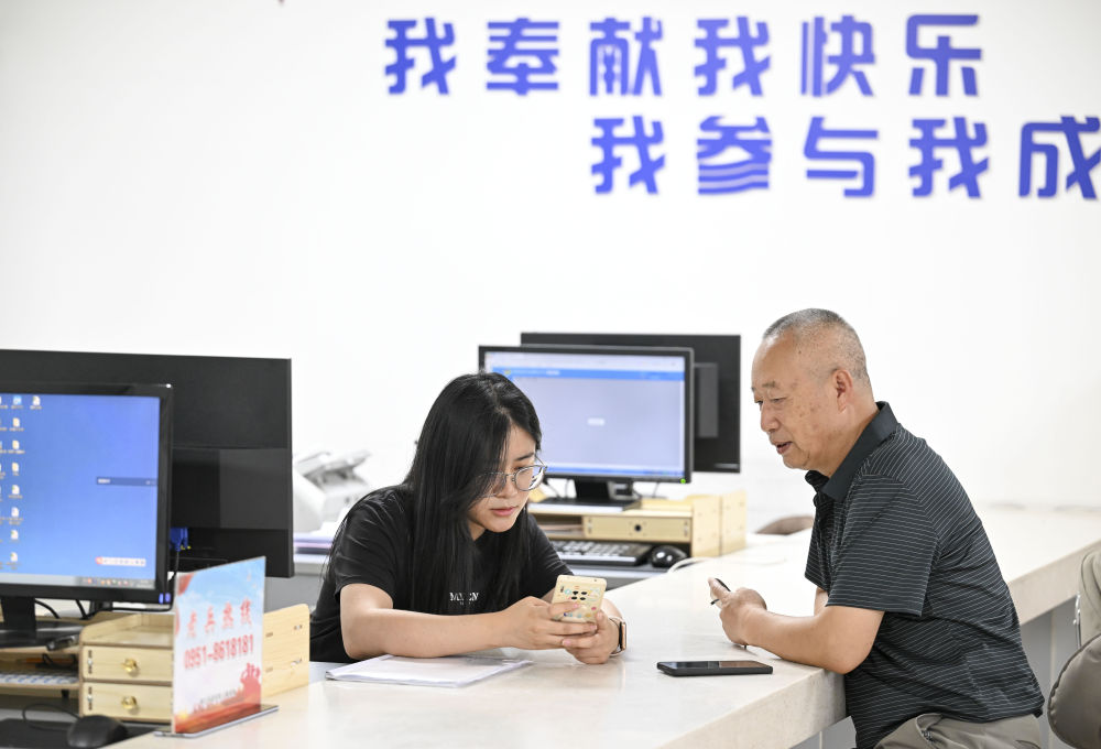 2024年6月20日，在寧夏銀川市金鳳區(qū)長(zhǎng)城花園社區(qū)黨群服務(wù)中心，工作人員幫助居民辦理業(yè)務(wù)。圖片來(lái)源 新華社